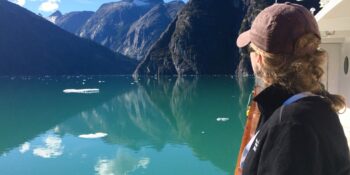 woman on small ship enjoying view of Alaskan Fjords