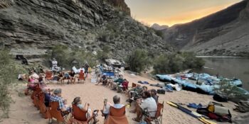 rafters eating all-inclusive dinner in the Grand Canyon with rafts in the background