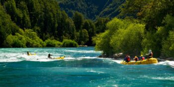 rafters running Isla Rapid on the Futaleufu River with white capped mountain in the background