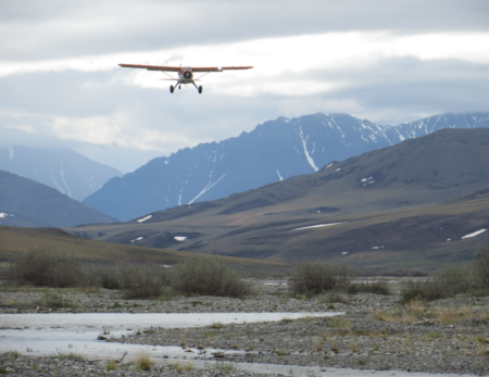 Coyote Air Beaver coming in for landing with Brooks range mountains and Kongakut river in the background